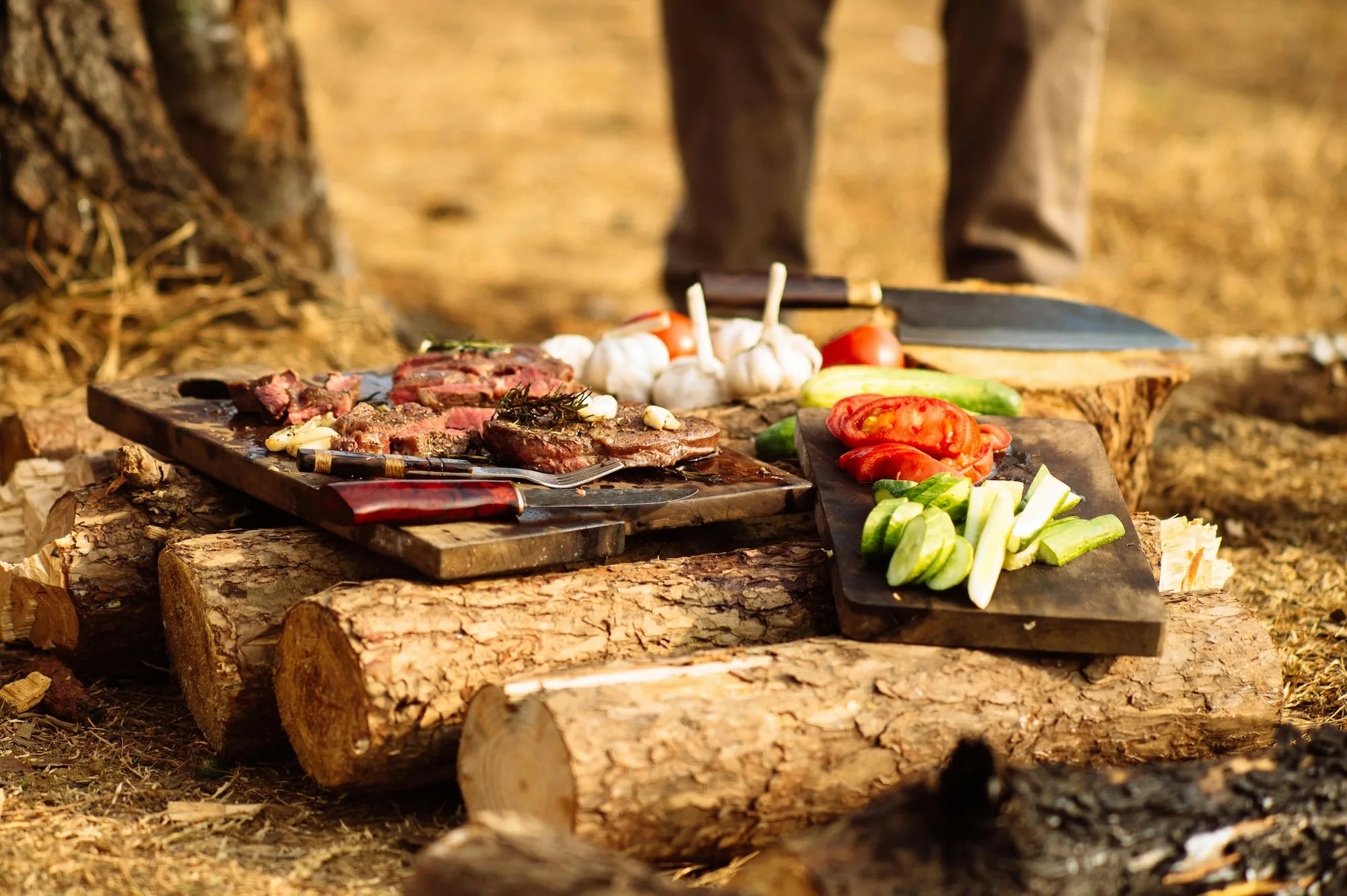Kött och grönsaker serverade på skärbrädor i trä utomhus vid lägereld